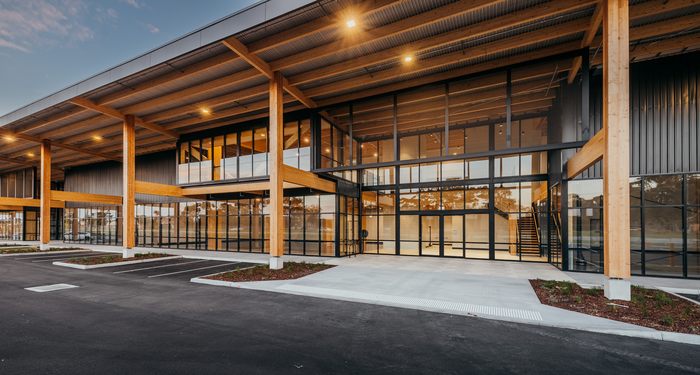 Modern, sustainably designed commercial building with extensive timber structure, glass façade, and shaded outdoor areas, showcasing environmentally conscious architecture