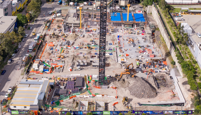 Aerial view of Goodman SYD01 data centre construction in Sydney, showing large crane, concrete foundations and active building site surrounded by buildings and city skyline.